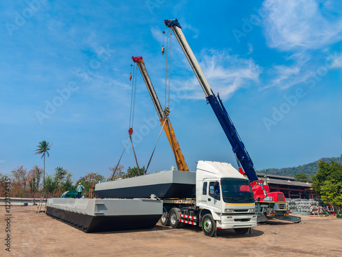 A Mobile Crane Lifts a Barge onto a Trailer for Transport from the Fabrication Shop to the River.