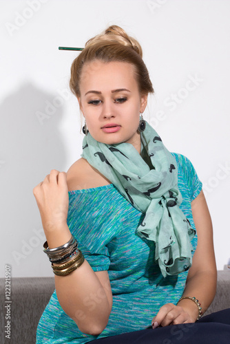 Obraz na płótnie Pensive woman with scarf and bracelets sitting on sofa w salonie