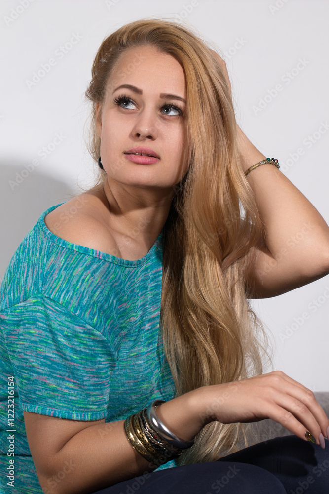 Portrait of a pensive blonde young woman in metal bracelets