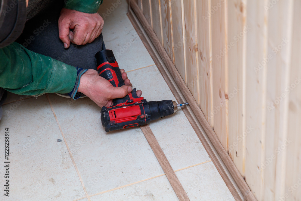 Φωτογραφία A man is using a power drill to make a hole in a wooden board
