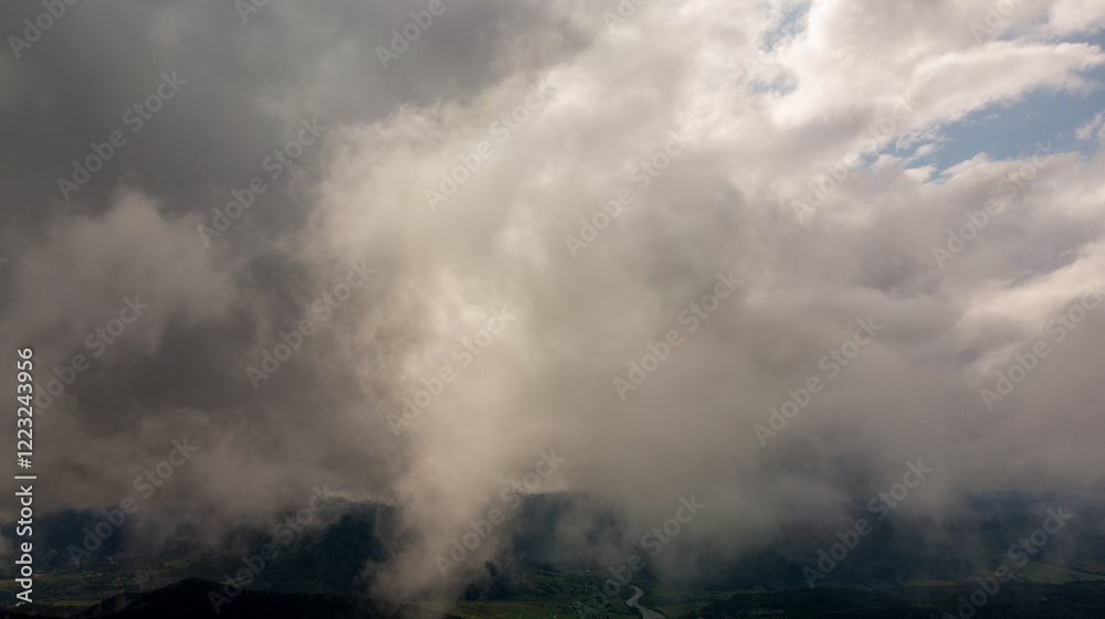 Aerial View Of Majestic Mountains Covered In Lush Green Forests, With Clouds Floating Above. The Sun Shines Brightly, Casting A Warm Glow Over The Breathtaking Landscape. Aerial View Of Majestic Mountains Covered In Lush Green Forests, With Clouds Floating Above. The Sun Shines Brightly, Casting A Warm Glow Over The Breathtaking Landscape.