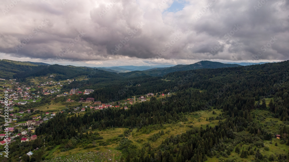 Naklejka premium Majestic Mountains, Lush Green Forests, And Dramatic Clouds With The Sun Casting A Golden Glow. Aerial View Capturing The Stunning Beauty Of Nature From A Bird’s-Eye Perspective. 