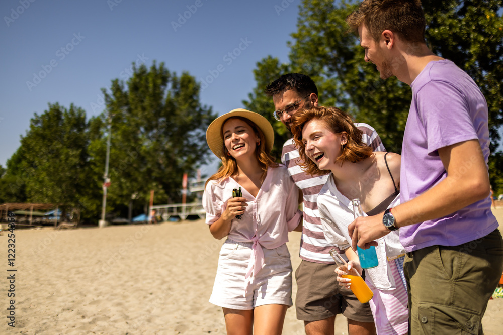Fototapeta premium Group of friends is smiling, dancing, having fun and they drink cocktails at the beach on a sunny day.