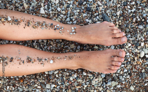 Exploring nature with bare feet on a pebbly shore under the sun photo