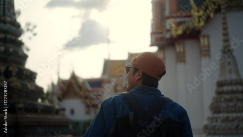 Happy young asian man using camera and enjoying culture landmark travel in temple Thailand, solo traveler capturing ancient pagoda memories on their adventure, tourist hipster camera photography.
