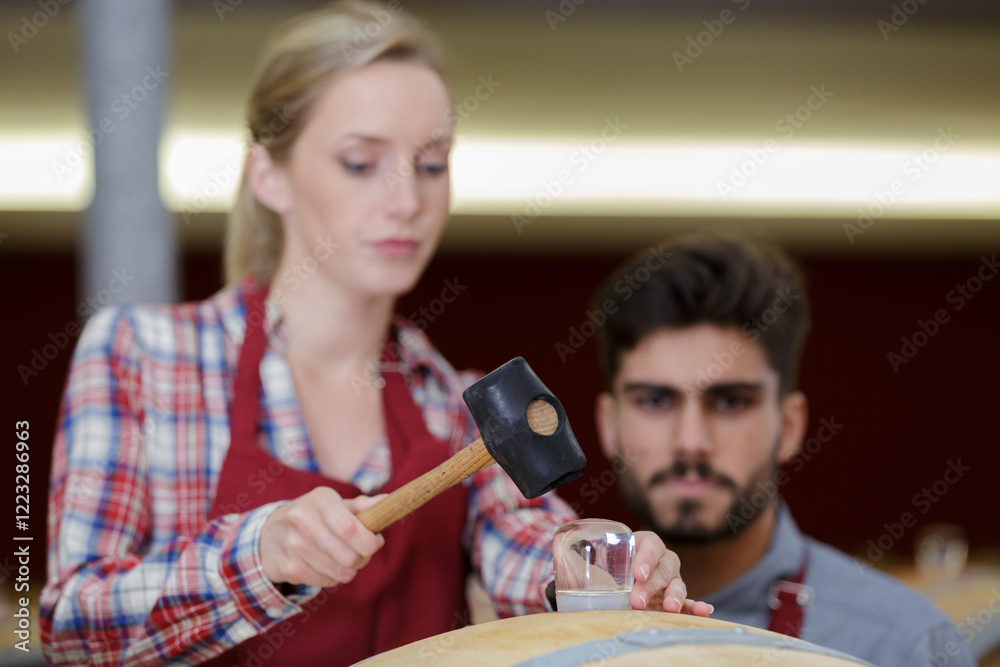 Fototapeta premium woman winery employee using a hammer in cellar