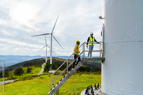 Engineer and operator working on a wind turbine platform, discussing maintenance and performance in a wind farm, contributing to sustainable energy production