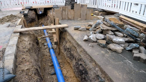 Construction site in a city street, deep trench and water pipes
