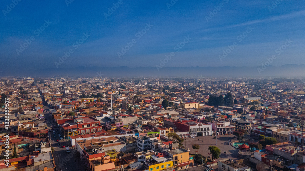 Fototapeta premium Aerial photography of the Nevado de Toluca landscape at sunset, with snow, clouds and a sky with ochre and red colors can be seen, in addition to a view of the magical town of Metepec.
