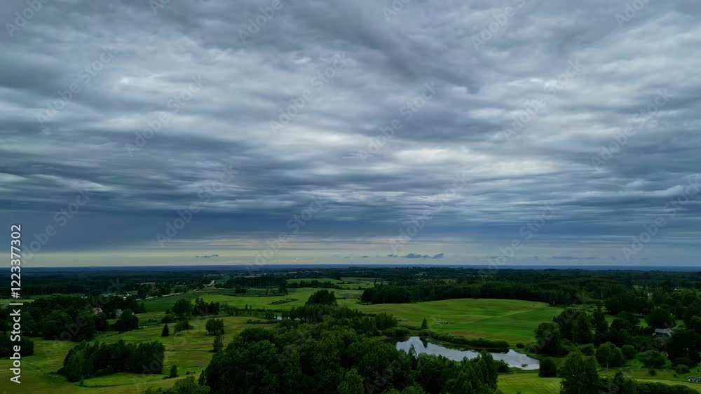 A serene aerial timelapse of lush green fields under dramatic cloudy skies A serene aerial timelapse of lush green fields under dramatic cloudy skies
