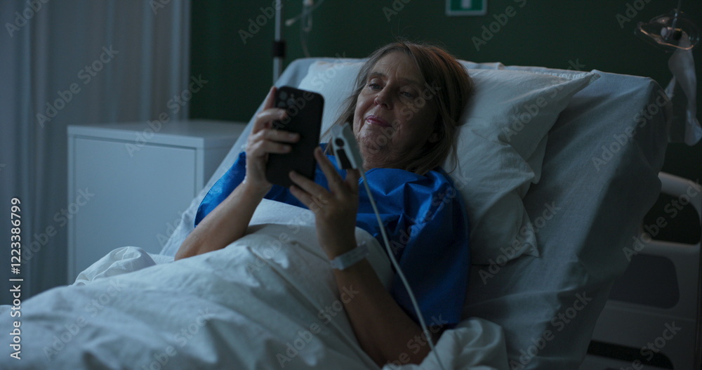 Obraz premium Photo shows elderly lady in hospital, looking at old photos on her phone.