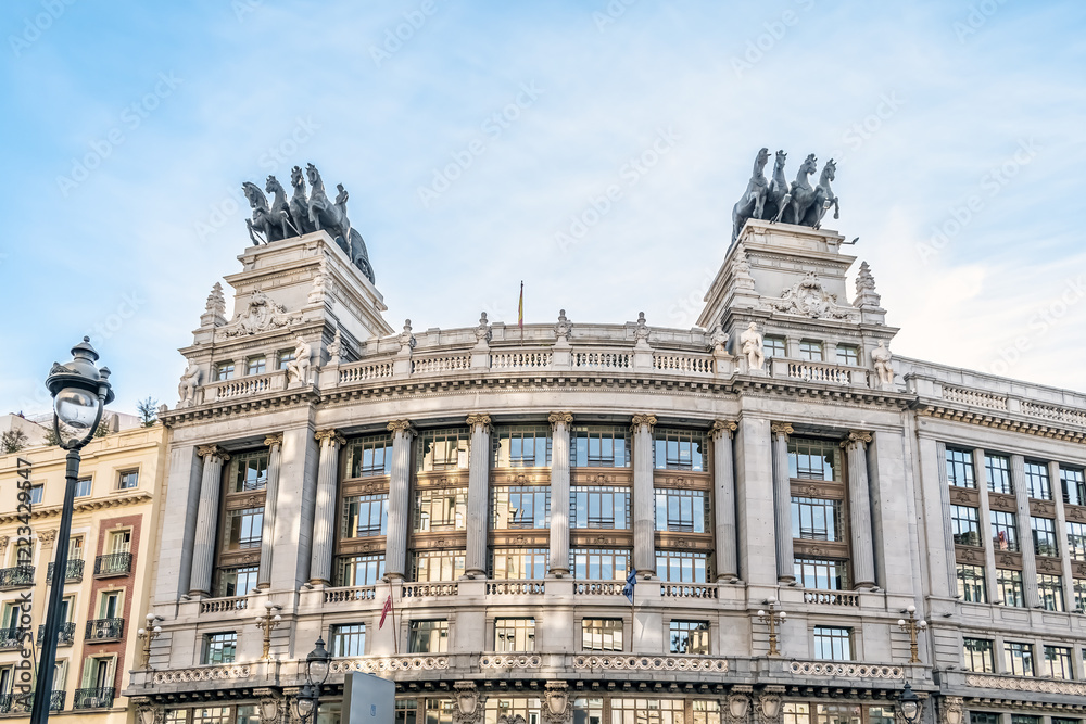 Fototapeta premium Facade of the historic Banco de Bilbao building in Madrid showcasing its classical architectural elements and and iconic chariots on the rooftop. Madrid, Spain - November 30, 2021