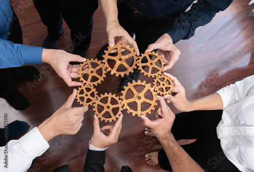 Business team joining cogwheel in circular together symbolize successful group of business partnership and strong collective unity teamwork in community workplace with productive efficiency. Prudent