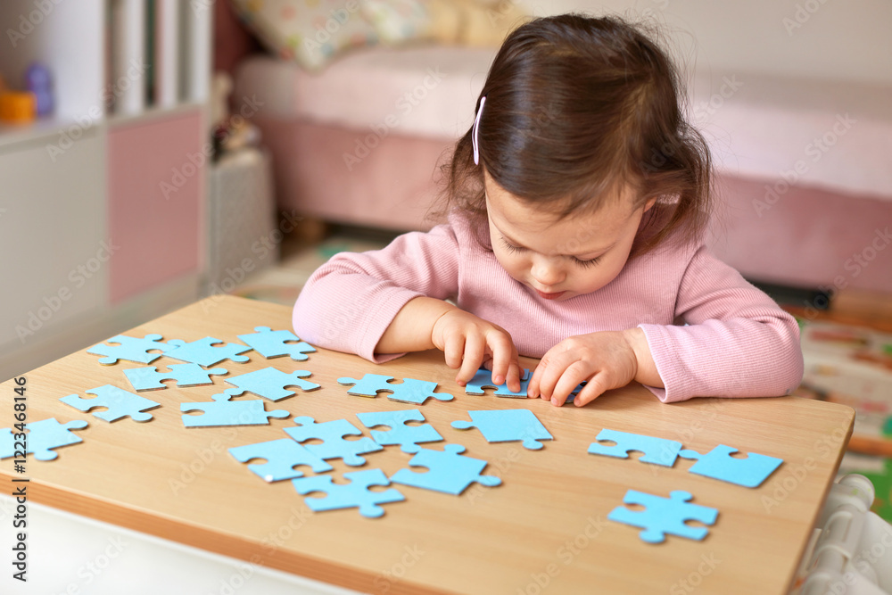 Cute little child girl connecting puzzle pieces on wooden desk in room, children development Cute little child girl connecting puzzle pieces on wooden desk in room, children development
