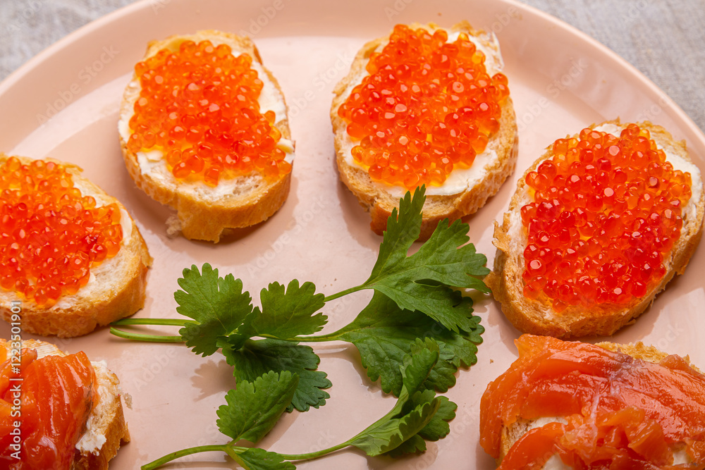Canapes with red caviar and salted salmon on a plate decorated with cilantro Canapes with red caviar and salted salmon on a plate decorated with cilantro