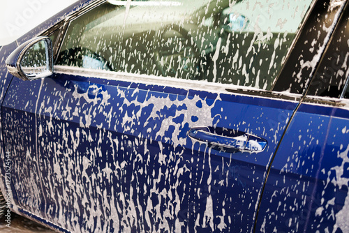 Close-up photo. Car parts with thick foam. Chemicals for washing dirty vehicles.