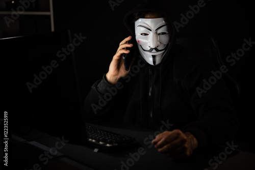 White smiling criminal anonymous mask calling to victim, convince to hack personal information, making share screen encryption program by hacker application on data server system in privacy. Surmise. photo