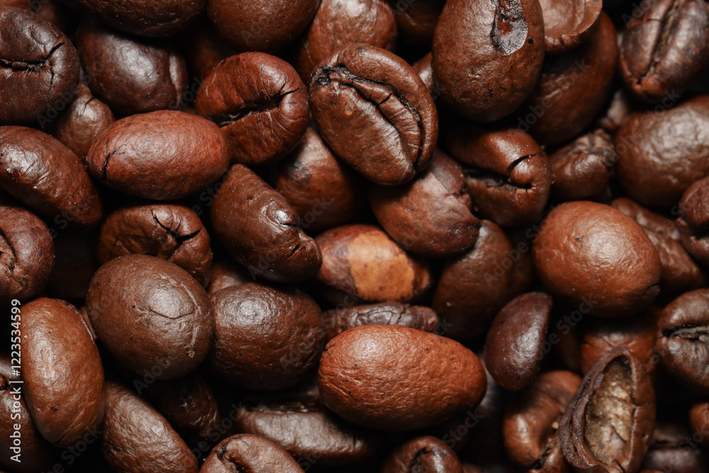 Naklejka premium A macro close-up of roasted coffee beans showcasing their rich brown color, detailed texture, and natural oils. The beans are tightly packed, emphasizing their unique shapes and surface patterns.
