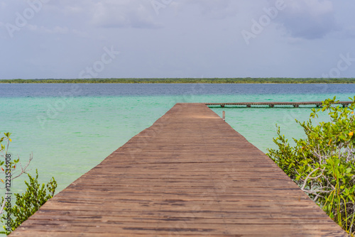 Wooden pier extending into the turquoise waters of Bacalar Lake, Mexico. Peaceful and scenic tropical destination. Travel, relaxation, and nature concept