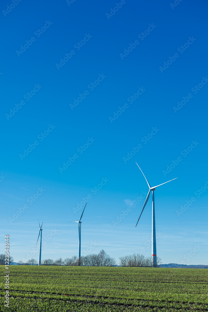 Wind energy generation. Electricity is generated by a wind turbine against a blue sky. Sustainable energy production in a windy green zone. Ecological energy generation Wind energy generation. Electricity is generated by a wind turbine against a blue sky. Sustainable energy production in a windy green zone. Ecological energy generation
