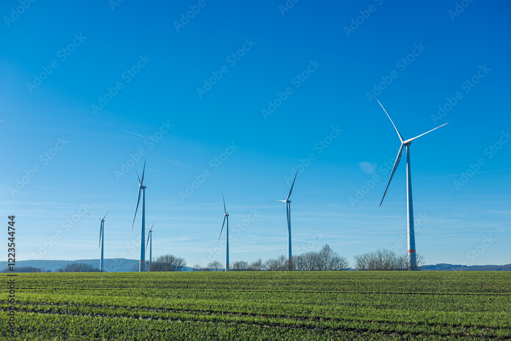 Wind energy generation. Electricity is generated by a wind turbine against a blue sky. Sustainable energy production in a windy green zone. Ecological energy generation Wind energy generation. Electricity is generated by a wind turbine against a blue sky. Sustainable energy production in a windy green zone. Ecological energy generation