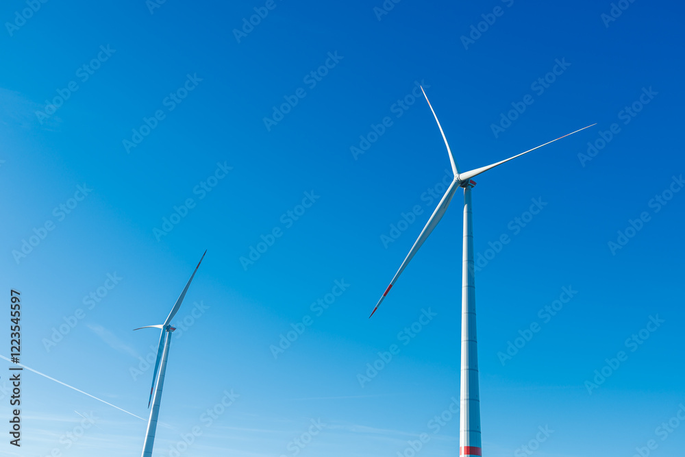 Wind energy generation. Electricity is generated by a wind turbine against a blue sky. Sustainable energy production in a windy green zone. Ecological energy generation
