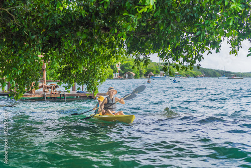 Obraz na płótnie Mother and son tourists kayaking on Bacalar Lake in Mexico. Adventure tourism in Quintana Roo, outdoor exploration, and water activities concept w salonie