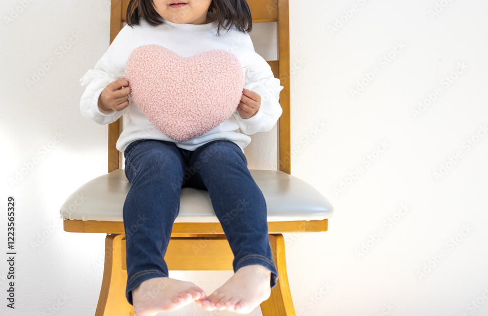 椅子に座ってハートのクッションを持つ女の子(日本人、4歳、顔無し)