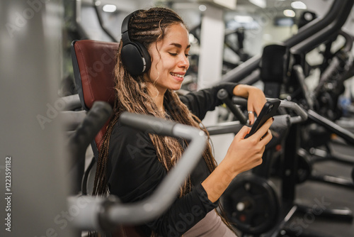 young woman with headphones use mobile phone and take a break at gym photo