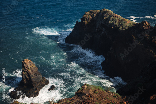 This breathtaking coastal view features steep cliffs with rocky outcrops, where waves crash against the shore. photo