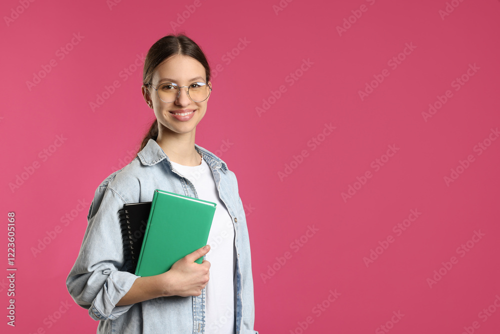 Portrait of smiling teenage girl with books on pink background. Space for text Portrait of smiling teenage girl with books on pink background. Space for text