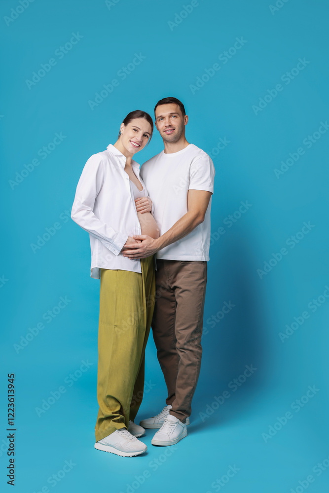 Pregnant woman and her husband on blue background Pregnant woman and her husband on blue background