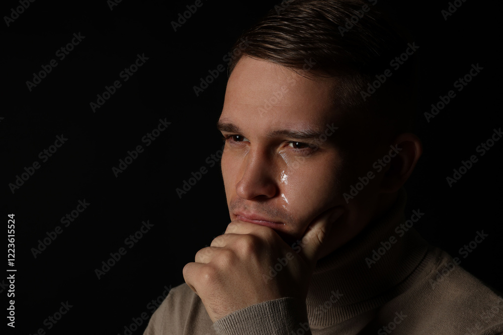 Distressed young man crying on black background. Space for text Distressed young man crying on black background. Space for text