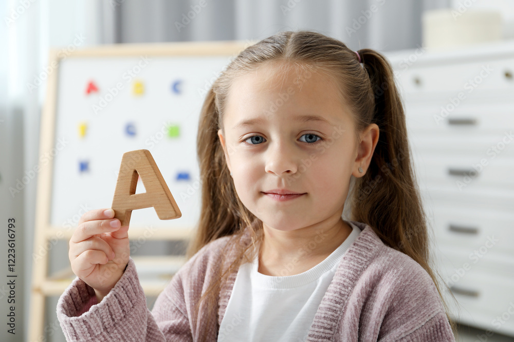 Learning alphabet. Little girl with wooden letter A indoors Learning alphabet. Little girl with wooden letter A indoors