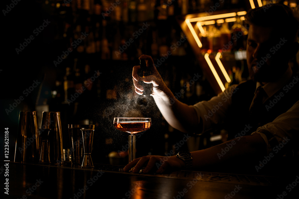 Naklejka premium Bartender sprays glass with brown cocktail, on bar counter