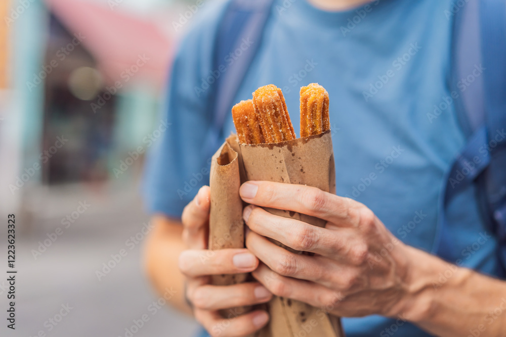 Male tourist eating churros on a colonial street in Puebla, Mexico. Cultural experience, local cuisine, and street food exploration concept