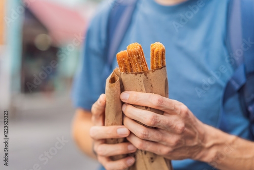 Male tourist eating churros on a colonial street in Puebla, Mexico. Cultural experience, local cuisine, and street food exploration concept