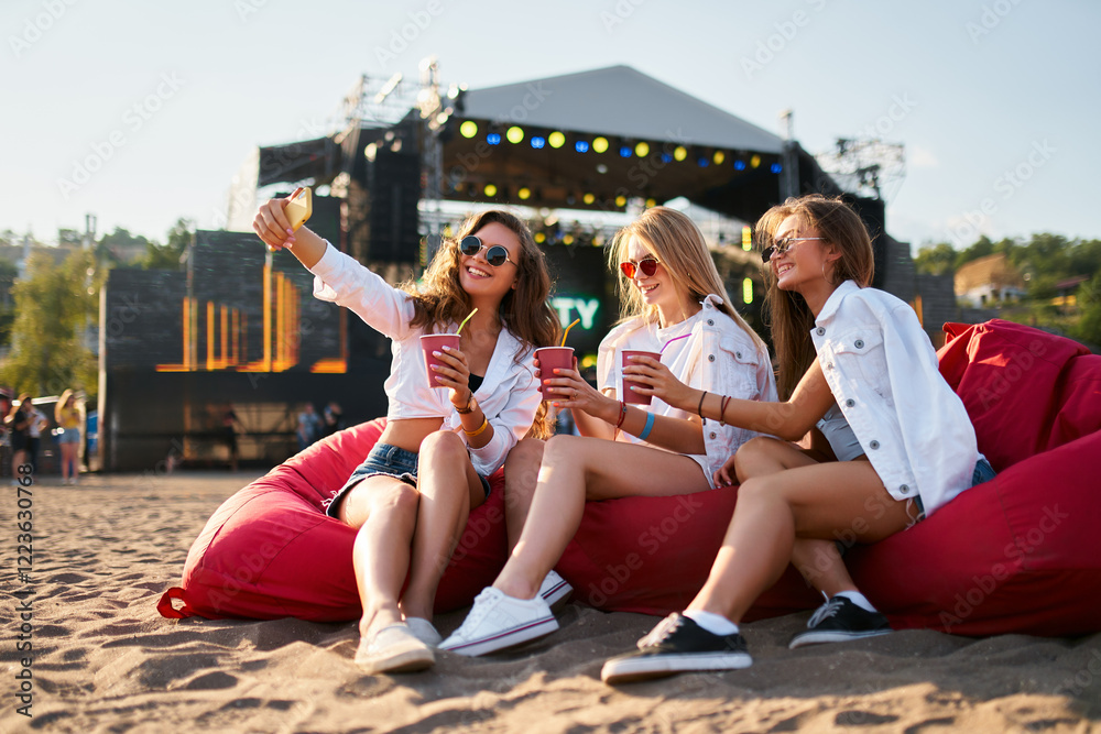 custom made wallpaper toronto digitalGroup of female friends enjoy summer music festival on sandy beach, sitting on red bean bag chairs, sipping cool drinks, stage in background. Happy women in casual attire relax, laugh.