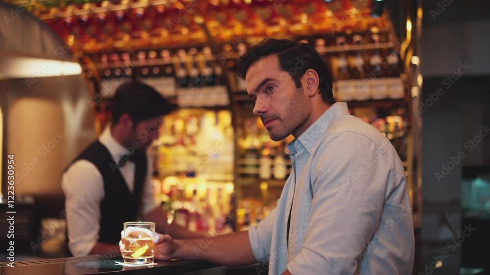 Smart man drinking cocktail in Old fashioned waiting friends or couple while bartender preparing drinks at special vibrant beverage counter bar warm light nightclub on Friday meeting night. Vinosity. Smart man drinking cocktail in Old fashioned waiting friends or couple while bartender preparing drinks at special vibrant beverage counter bar warm light nightclub on Friday meeting night. Vinosity.