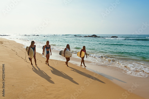 Photography Four friends walk with surfboards on sandy beach