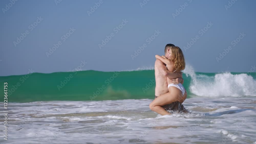 Fit man carrying woman in sea surf waves, water makes splashes. Happy couple in love having fun in the ocean. Tanned boyfriend and girlfriend enjoying romantic trip in the peaceful place. Fit man carrying woman in sea surf waves, water makes splashes. Happy couple in love having fun in the ocean. Tanned boyfriend and girlfriend enjoying romantic trip in the peaceful place.