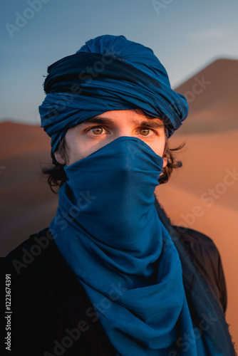 Caucasian male tourist wearing blue turban and shemagh in the sahara desert at sunset, merzouga, morocco photo