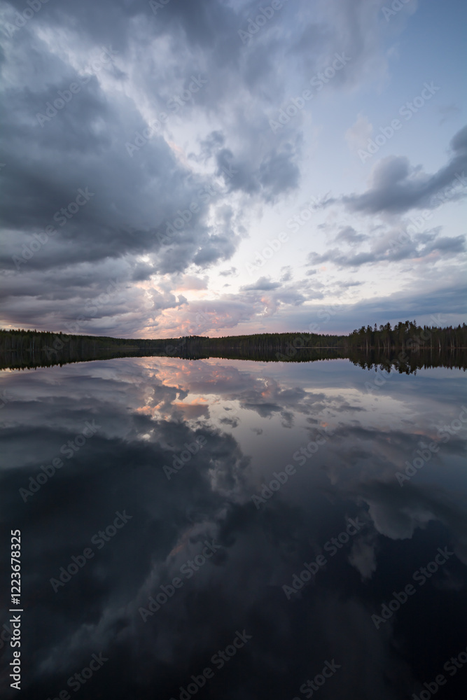 Obraz premium Clouds and forests reflected on the surface of a calm lake in Finland