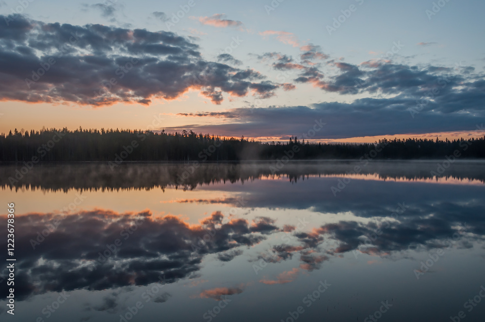 Fototapeta premium Clouds and forests reflected on the surface of a calm lake in Finland