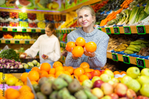 Portrait of young female choosing fresh oranges in fruit store photo