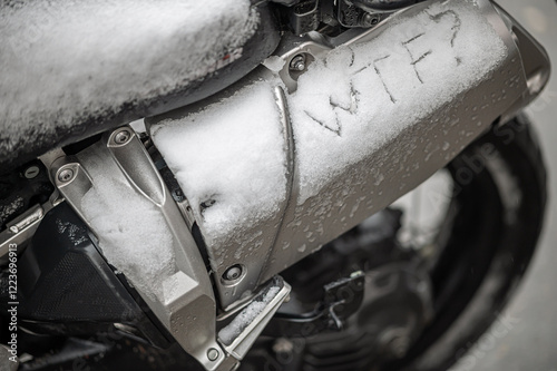 A large black touring motorcycle is covered in snow. The end of the motorcycle season, winter. The inscriptions 