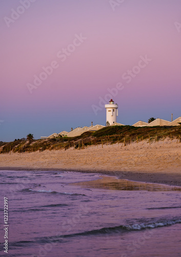 Obraz na płótnie Vertical shot of Woodbridge Island Lighthouse during a stunning sunset twilight, with warm golden hues reflecting on the calm waters, Cape Town, South Africa w salonie