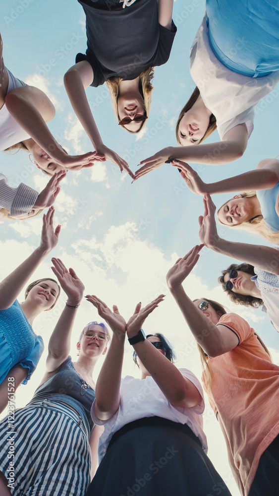 © Довидович Михаил - School friends joining hands to form heart shape against cloudy sky, representing unity, friendship, and teamwork