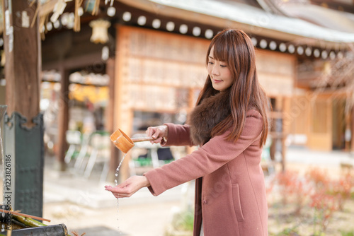 A shrine in Hakata, Fukuoka, Japan. A Japanese woman with a long hair in her thirties cleans her hands using a ladle.