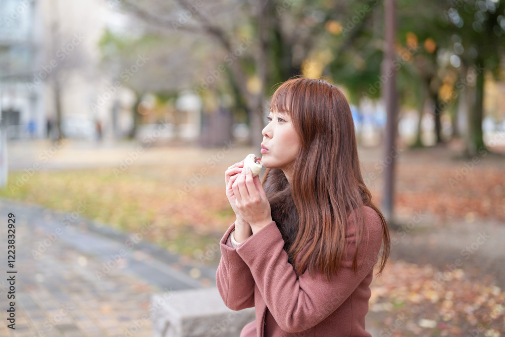A park with beautiful autumn leaves. Japanese women with long hair in their thirties eat meat buns. A park with beautiful autumn leaves. Japanese women with long hair in their thirties eat meat buns.
